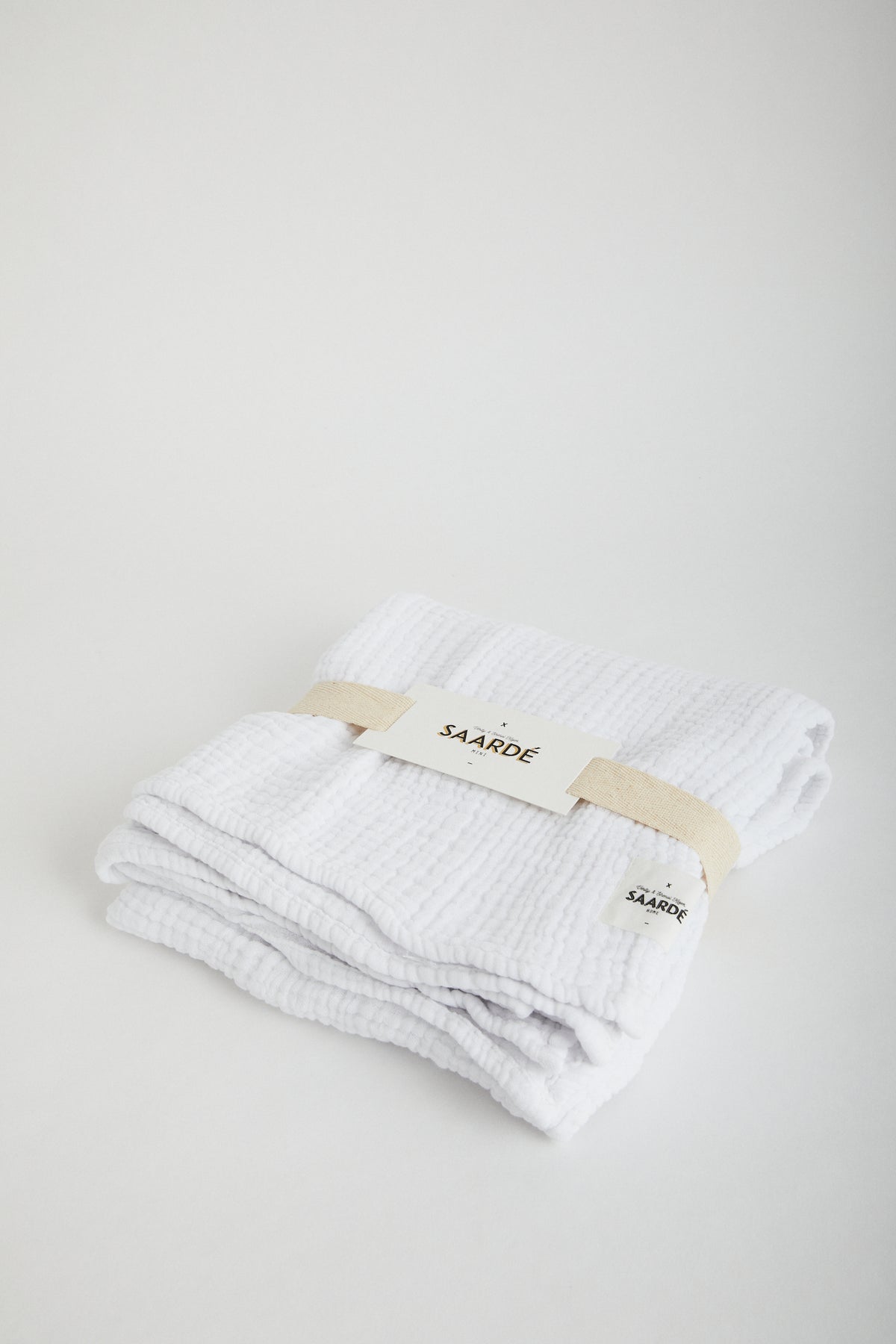 Muslin Crinkle Baby Blanket in White. Saarde logo stitched on corner. Wrapped in cotton ribbon.