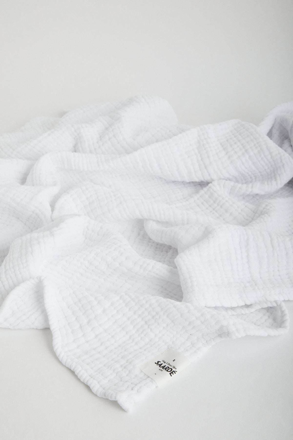 Muslin Crinkle Baby Blanket in White. Saarde logo stitched on corner.