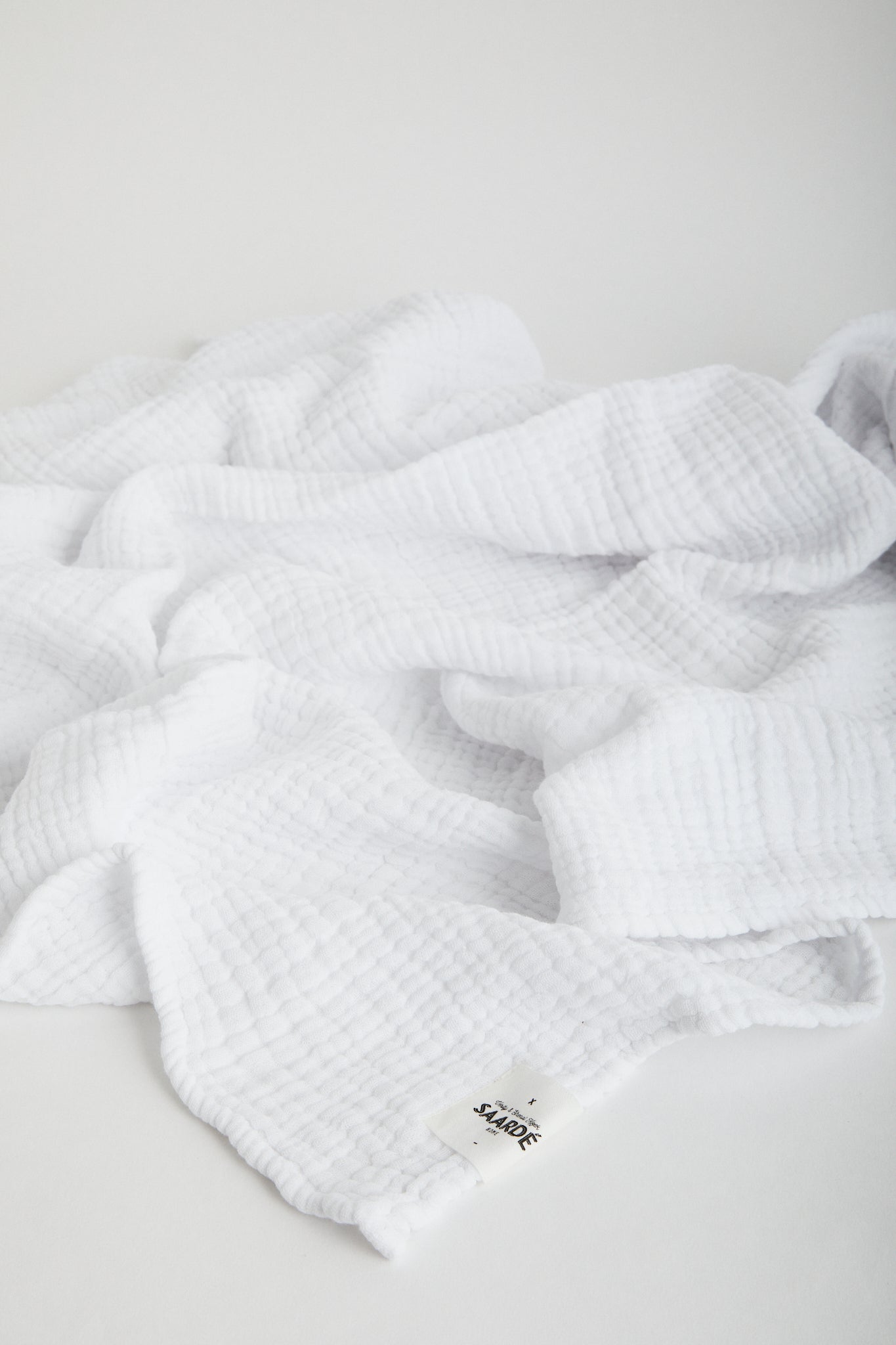 Muslin Crinkle Baby Blanket in White. Saarde logo stitched on corner.
