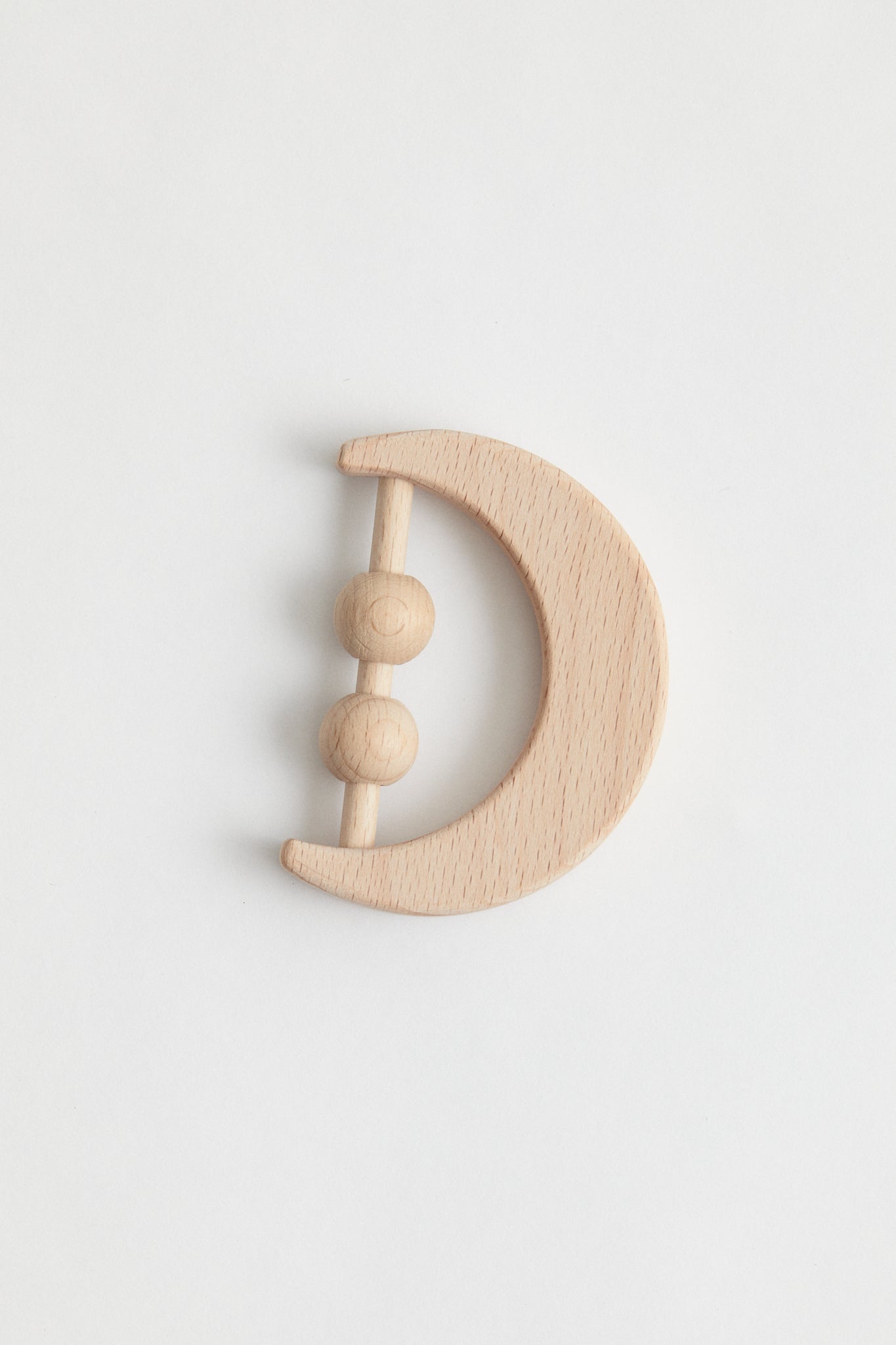Crescent moon shaped rattle made from beech wood. Two beads for sound when shaking.