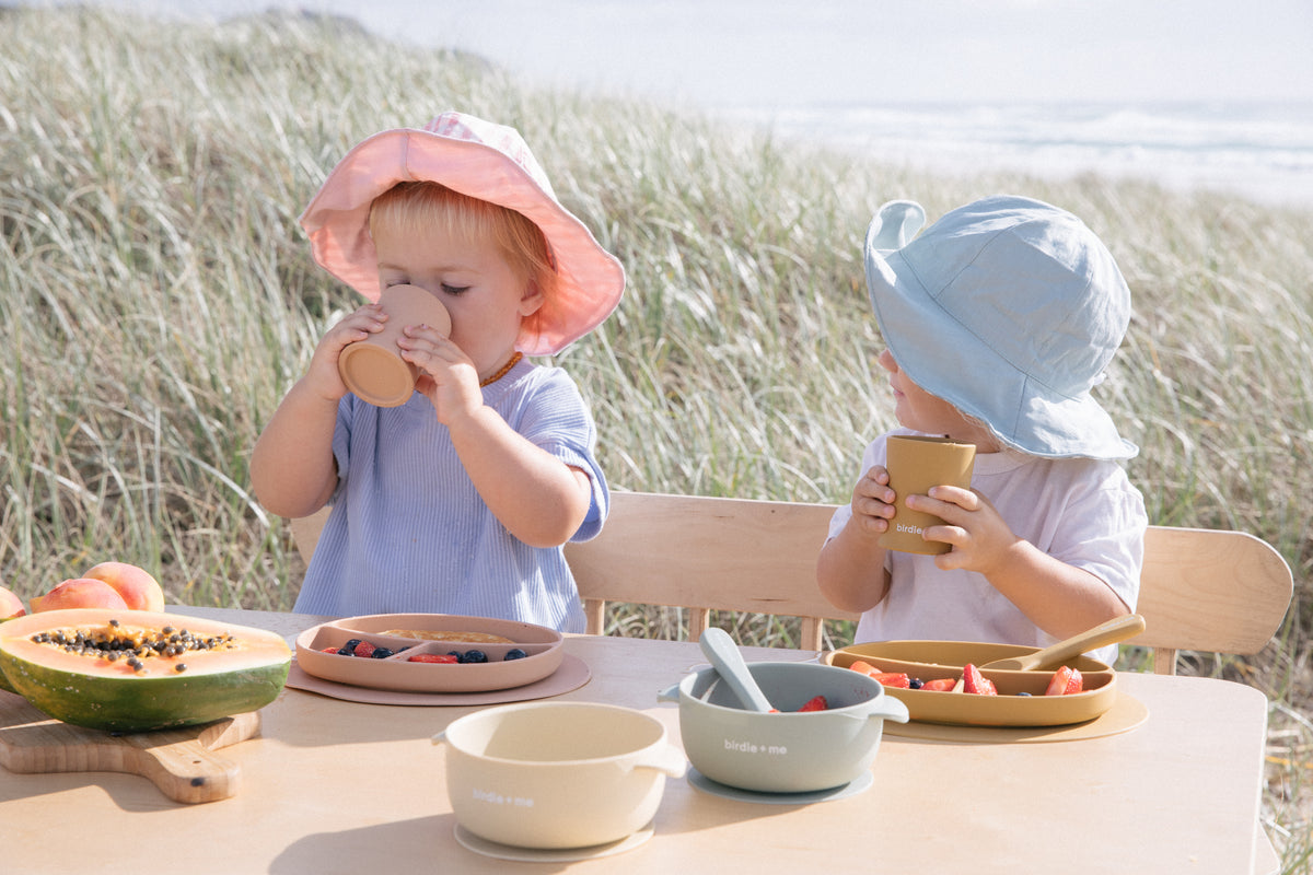 Toddlers drinking from silicone cups.