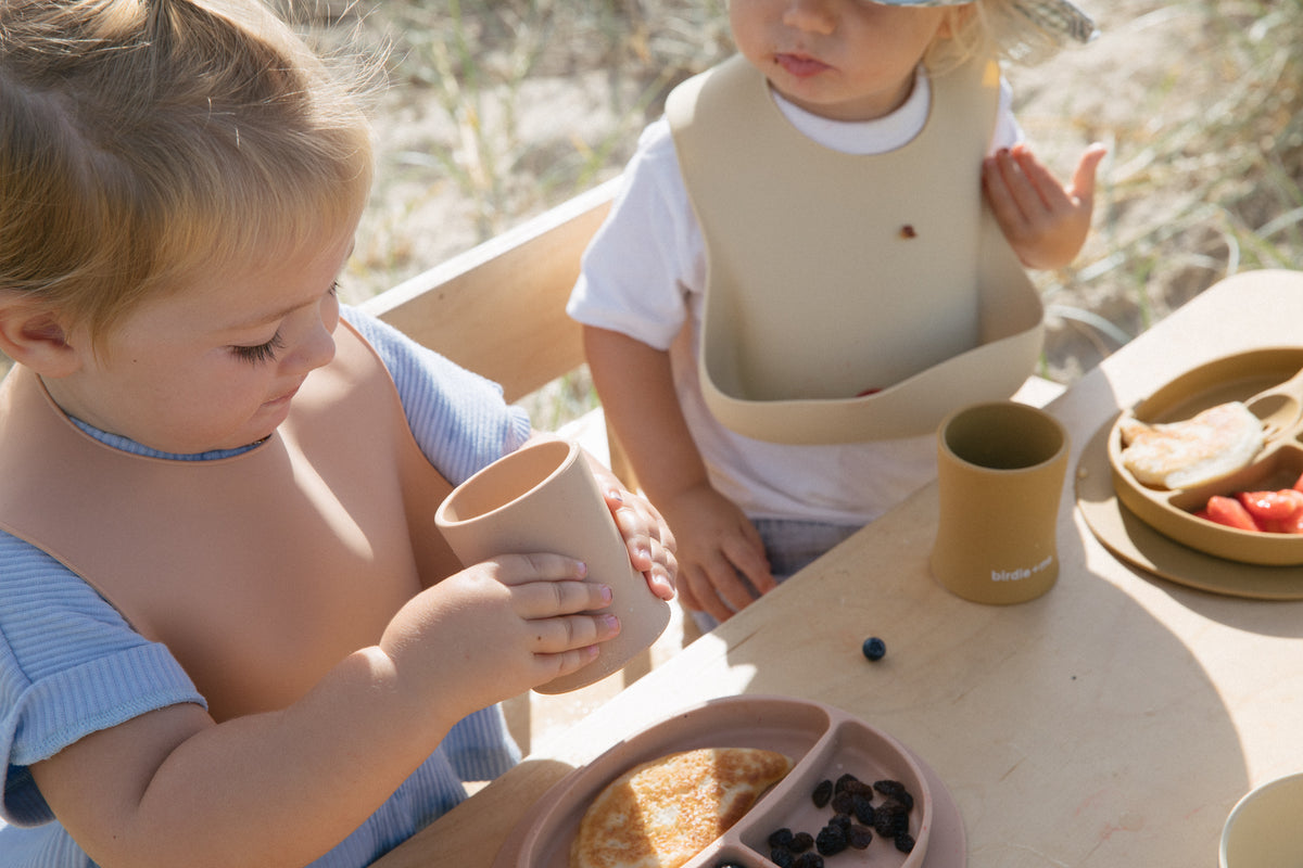 Toddlers drinking from silicone cups.