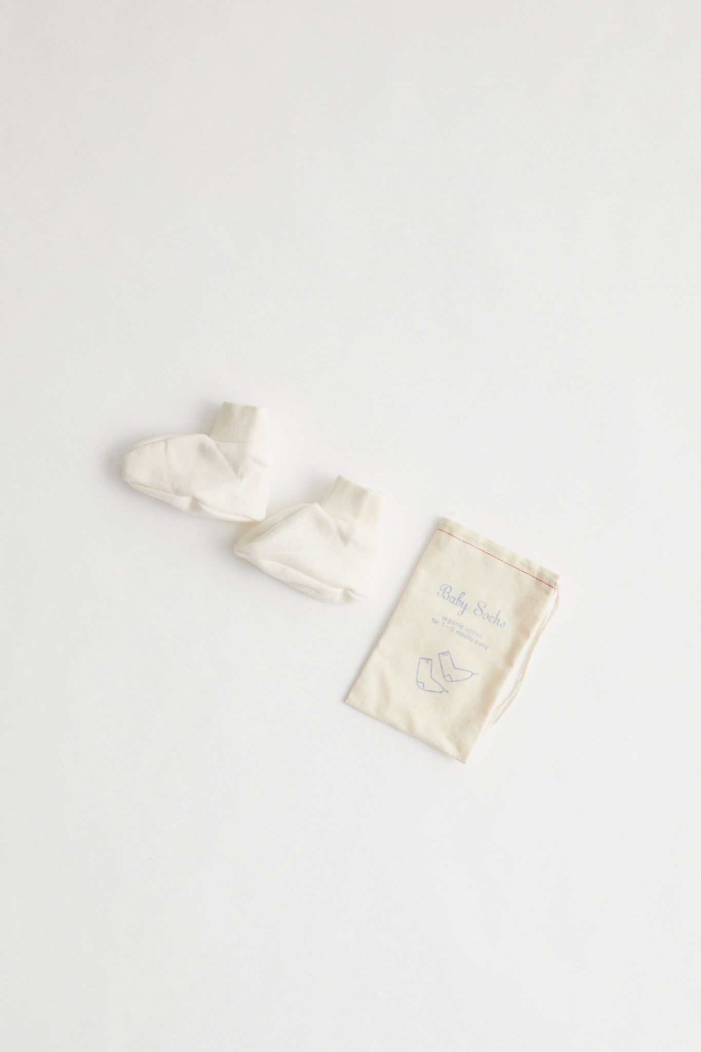 Organic cotton baby booties in natural colour, packaged in muslin drawstring bag