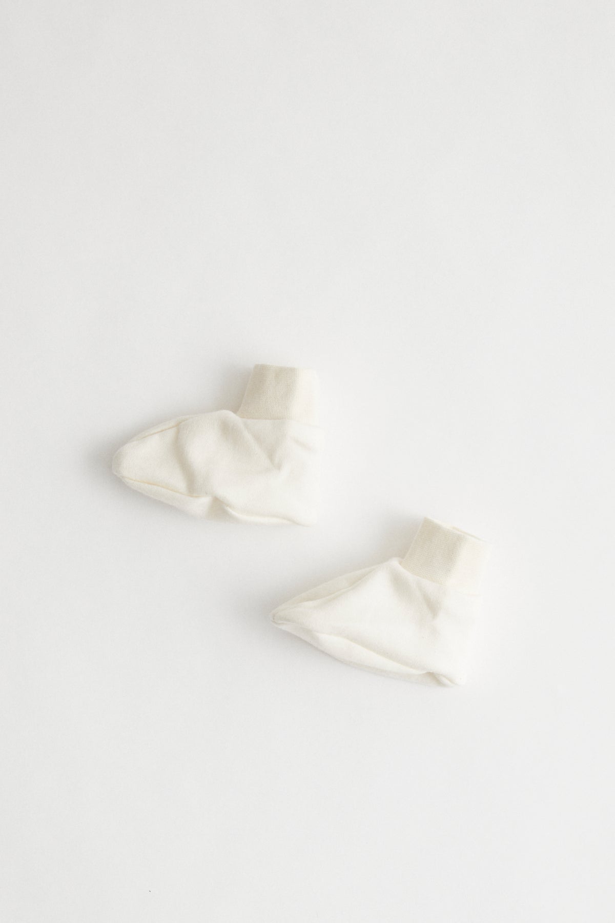Organic cotton baby booties in natural colour, packaged in muslin drawstring bag