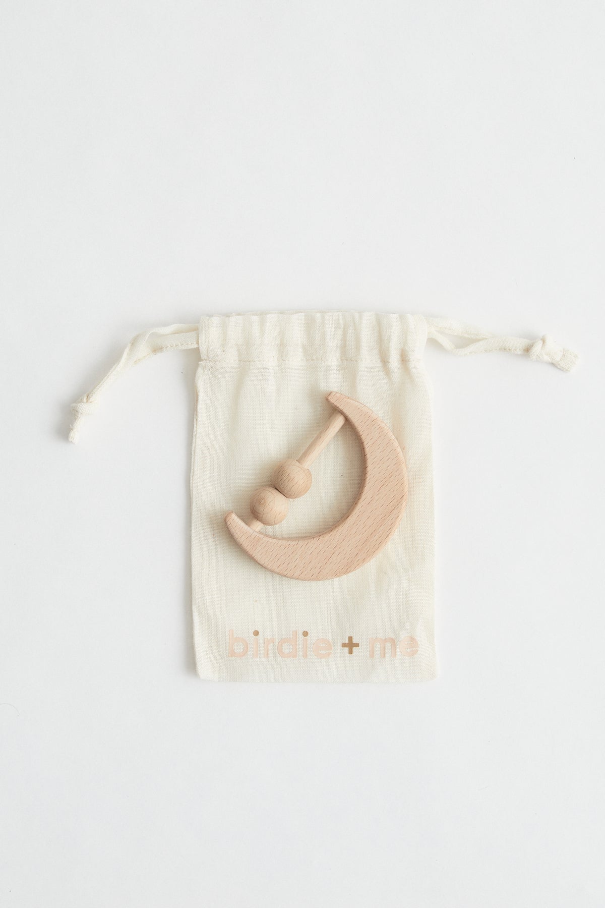 Crescent moon shaped rattle made from beech wood with two beads. packaged in birdie + me calico bag