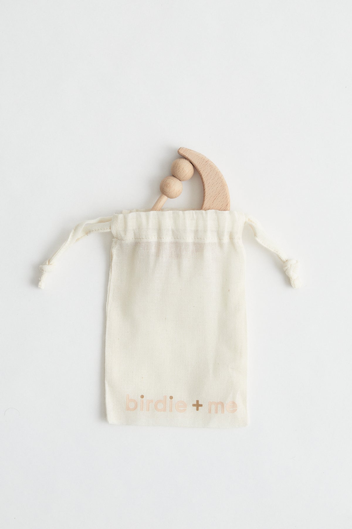Crescent moon shaped rattle made from beech wood with two beads. packaged in birdie + me calico bag