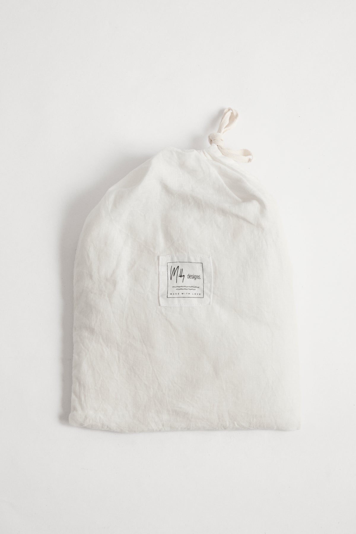 White linen cot sheet in white linen drawstring bag.