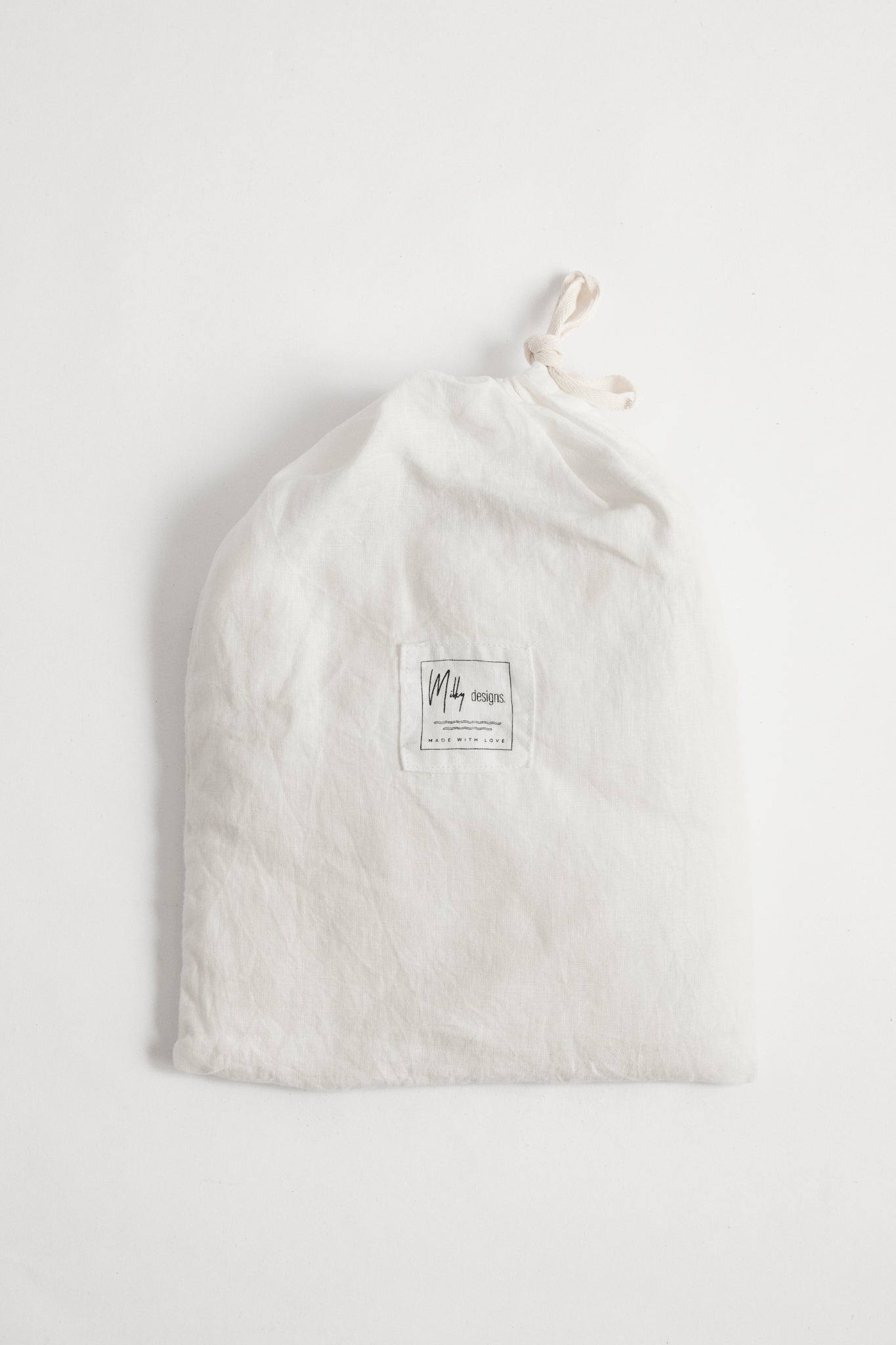 White linen cot sheet in white linen drawstring bag.