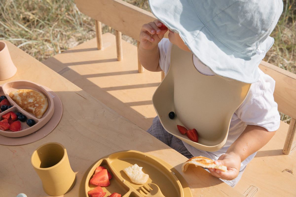 Silicone bib in Clay worn by toddler.